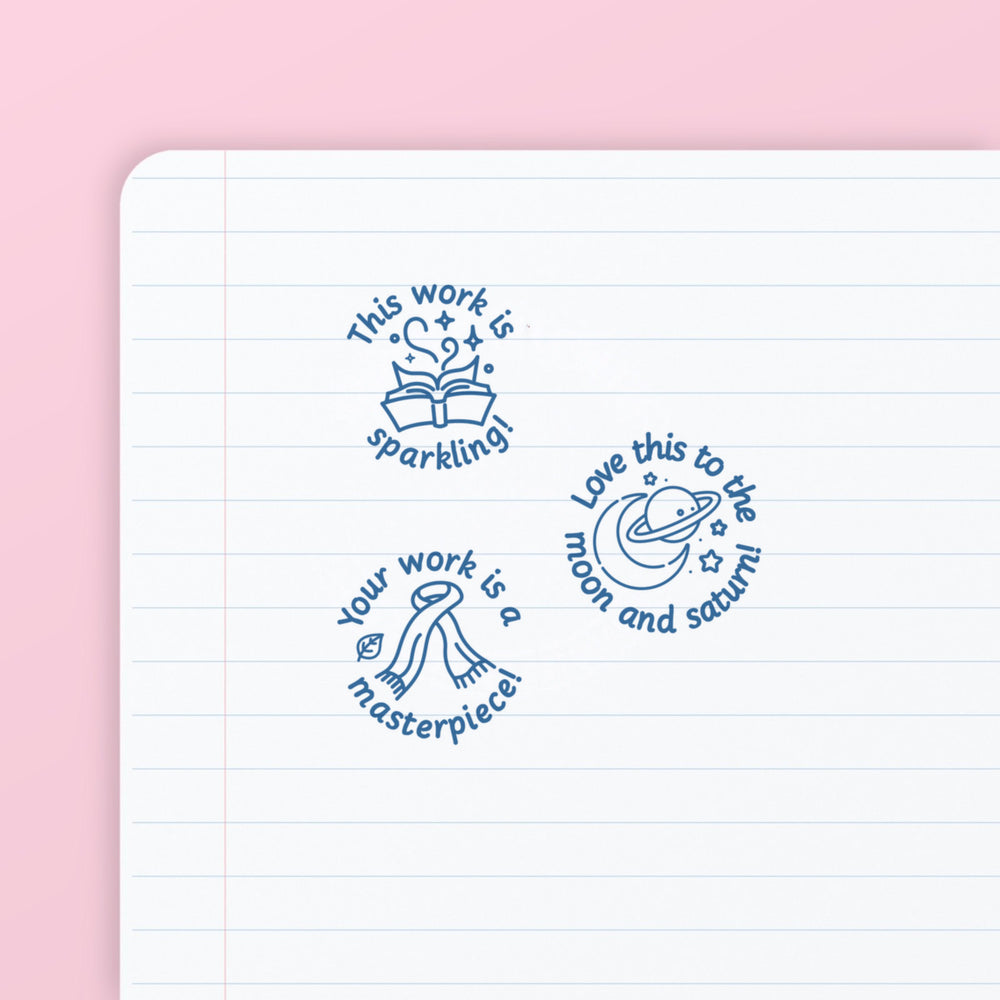 Pop Star Stamp Set 1 - the three teacher marking stamps in the set, stamped in blue ink on lined paper: sparkling, moon and saturn, and masterpiece. My Teacher Says, handmade in Scotland.