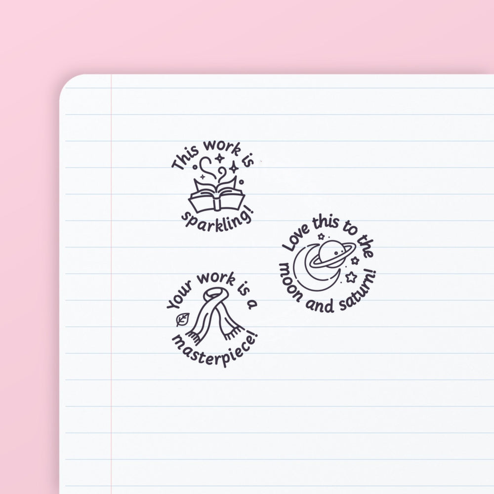 Pop Star Stamp Set 1 - the three teacher marking stamps in the set, stamped in purple ink on lined paper: sparkling, moon and saturn, and masterpiece. My Teacher Says, handmade in Scotland.