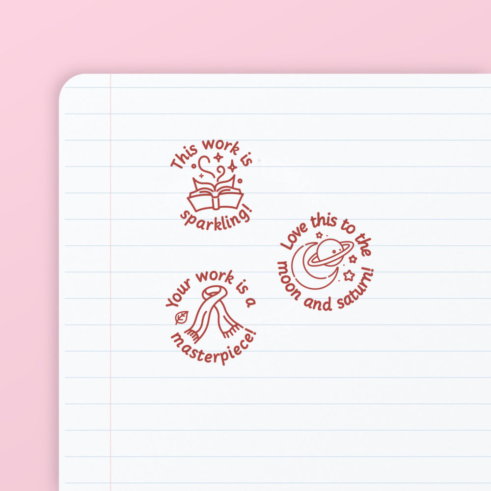 Pop Star Stamp Set 1 - the three teacher marking stamps in the set, stamped in red ink on lined paper: sparkling, moon and saturn, and masterpiece. My Teacher Says, handmade in Scotland.